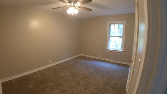 an empty room with windows and fan