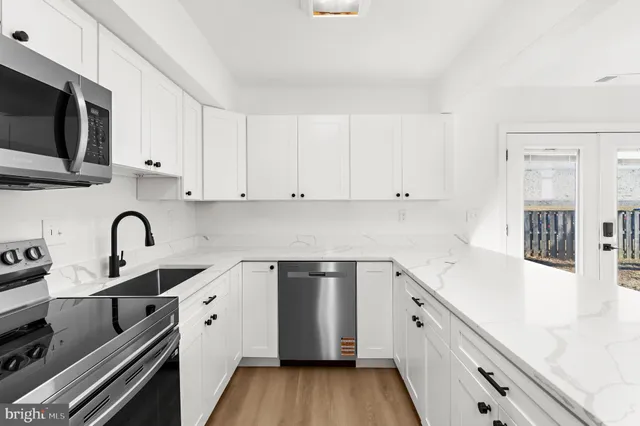 a kitchen with stainless steel appliances white cabinets a sink and a stove