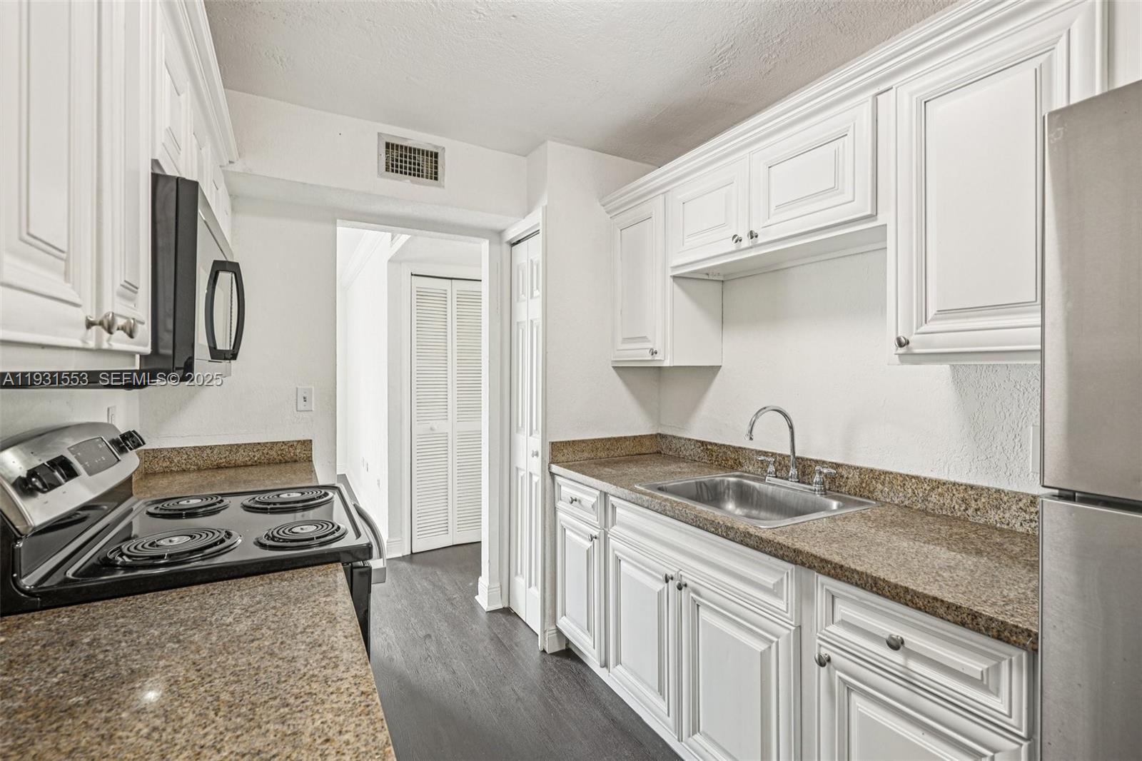 a kitchen with stainless steel appliances granite countertop a sink stove oven and white cabinets with wooden floor