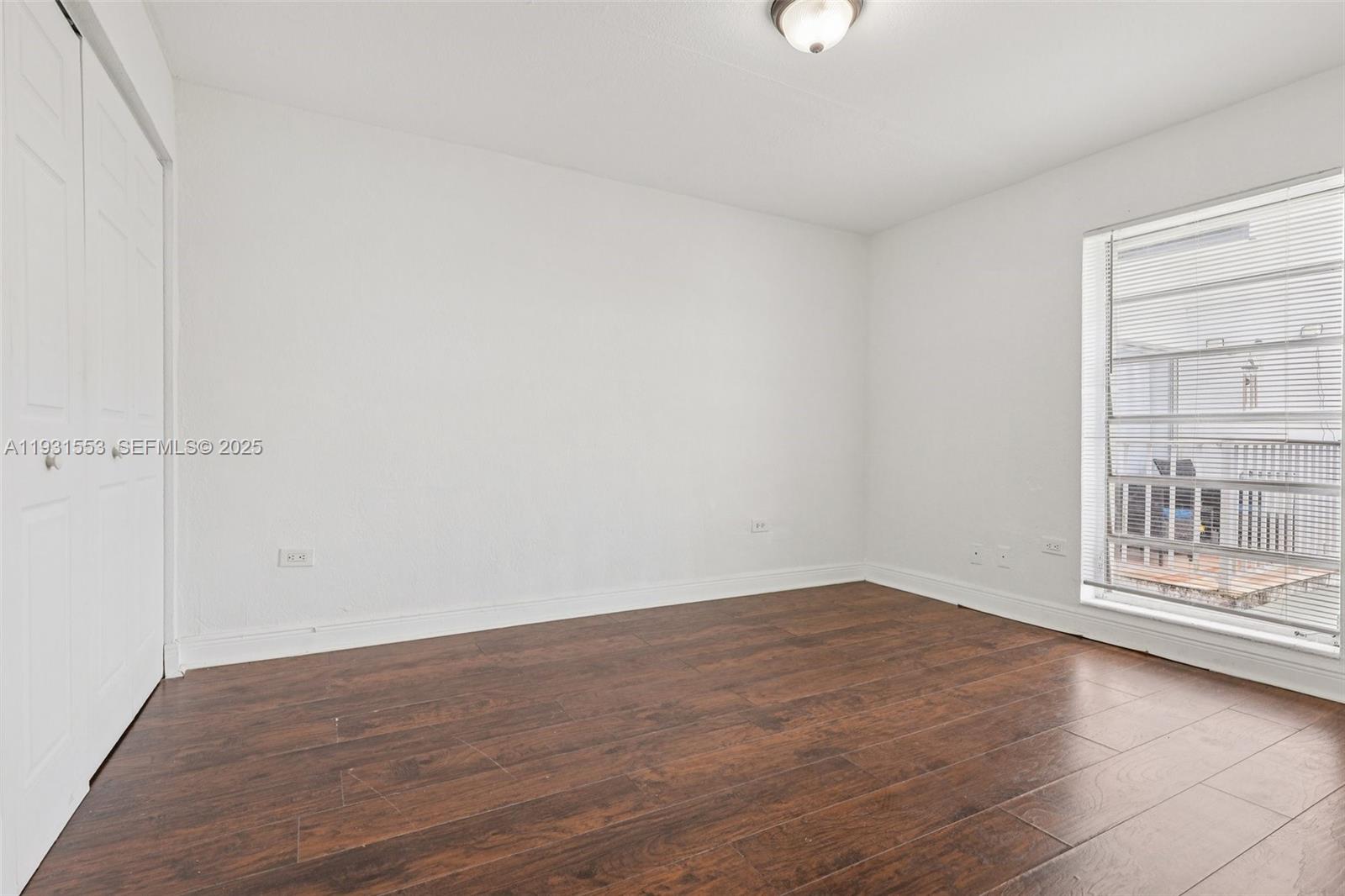 7232 Southwest 94th Place, Unit E6 Miami, FL 33173 - Photo 12 of 31 a view of an empty room with wooden floor and a window