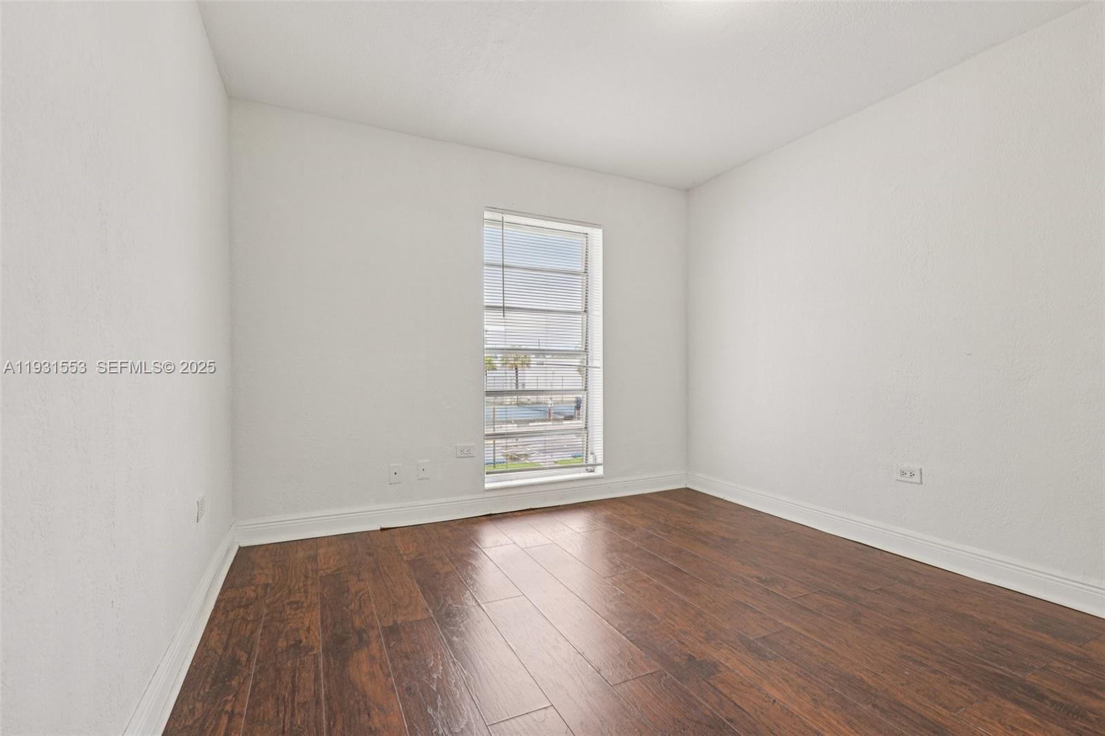 7232 Southwest 94th Place, Unit E6 Miami, FL 33173 - Photo 13 of 31 an empty room with wooden floor and window