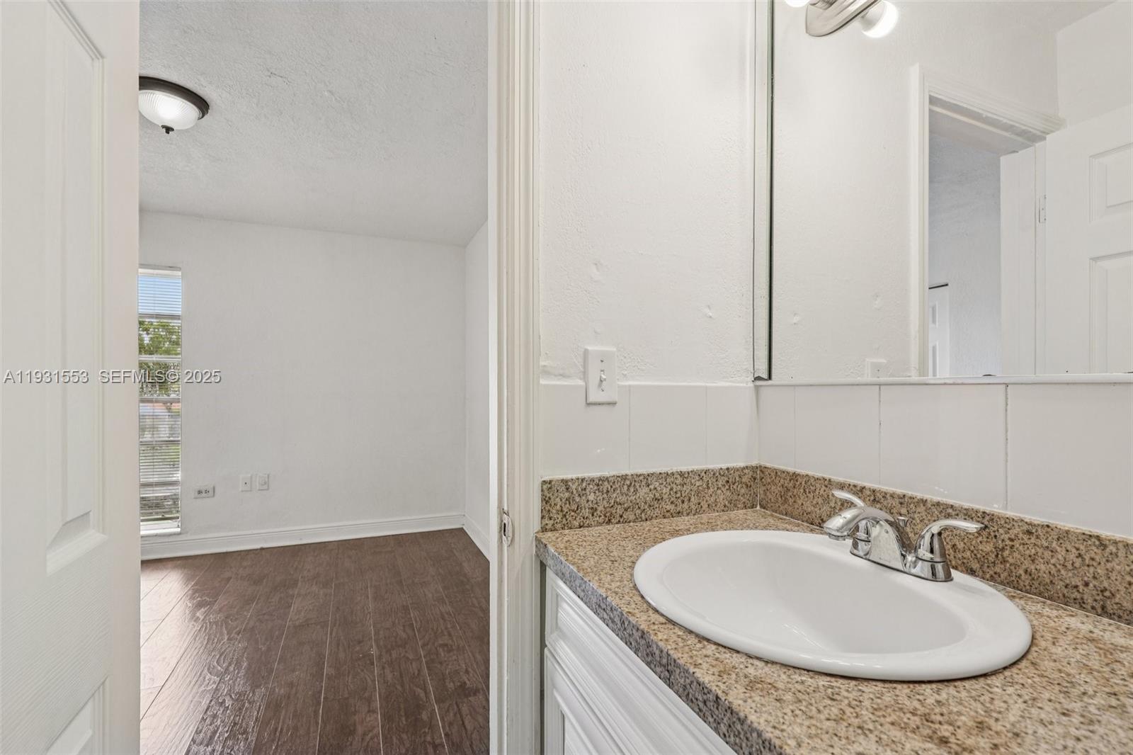 7232 Southwest 94th Place, Unit E6 Miami, FL 33173 - Photo 23 of 31 a bathroom with a granite countertop sink and a mirror