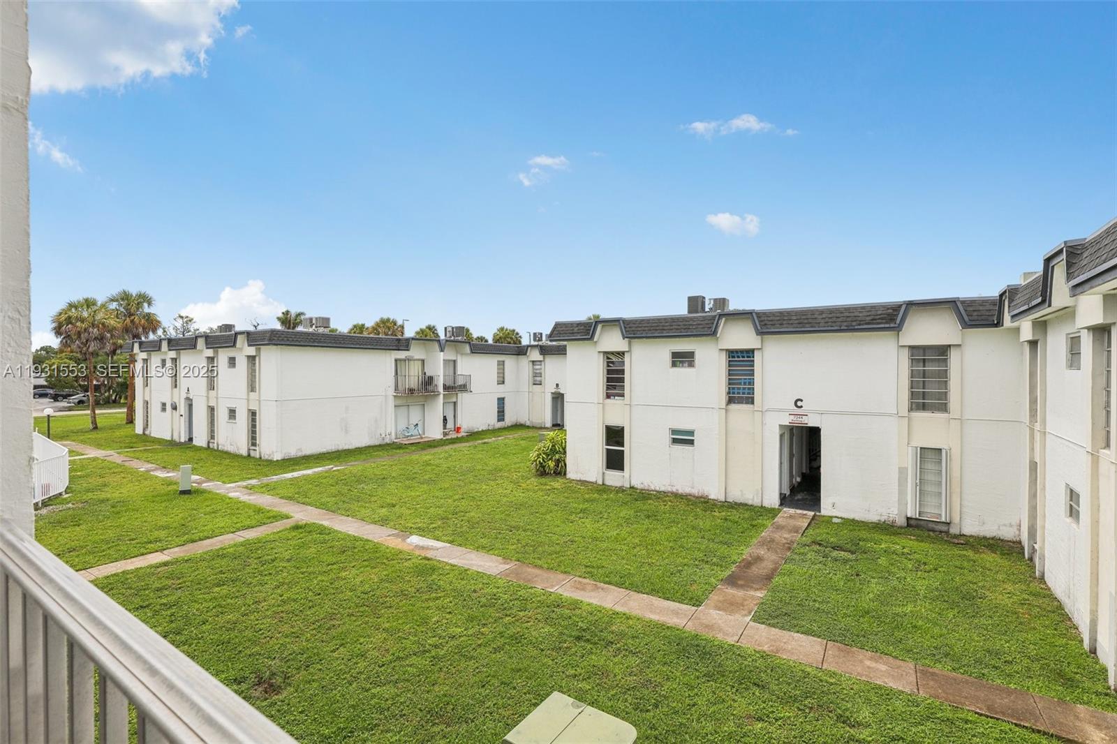 7232 Southwest 94th Place, Unit E6 Miami, FL 33173 - Photo 27 of 31 a view of a white house in front of a big yard with plants and large trees