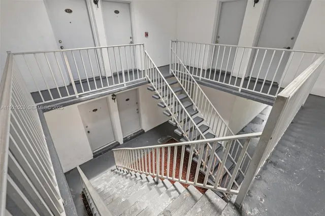 a view of staircase with railing and white walls