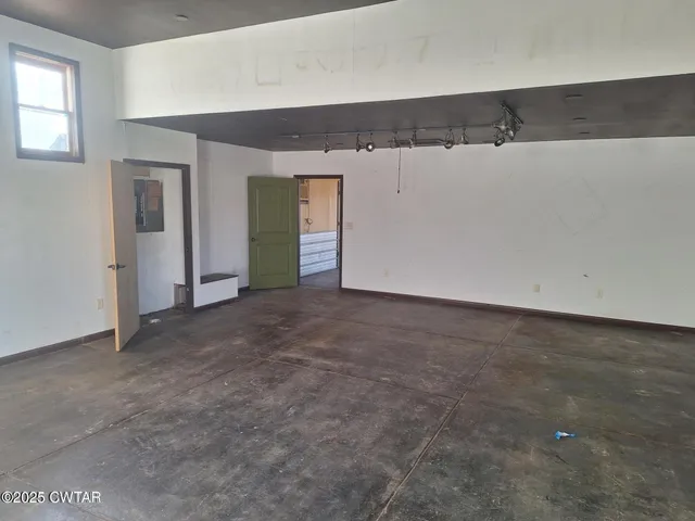 a view of a refrigerator in kitchen and an empty room