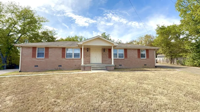 a view of a house with a yard and large tree