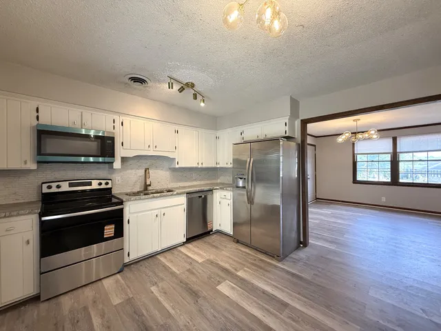a kitchen with granite countertop a refrigerator and a stove top oven