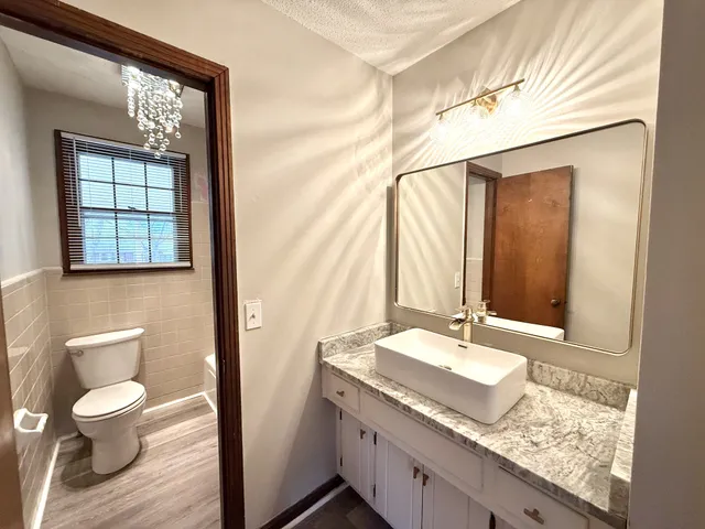 a bathroom with a granite countertop sink toilet and mirror