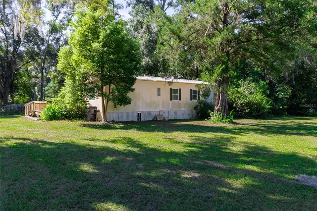 a backyard of a house with plants and large trees