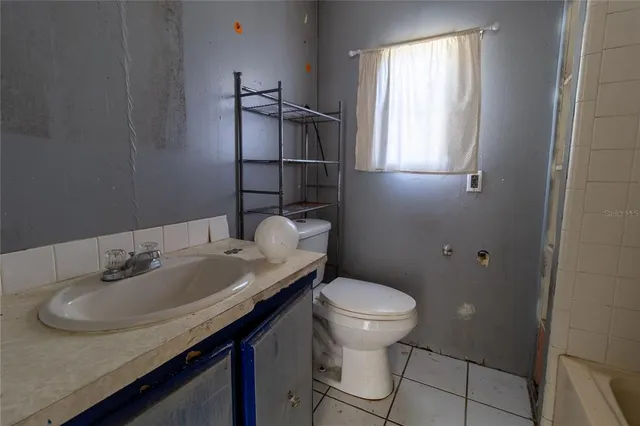 an empty room with wooden floor chandelier fan and windows