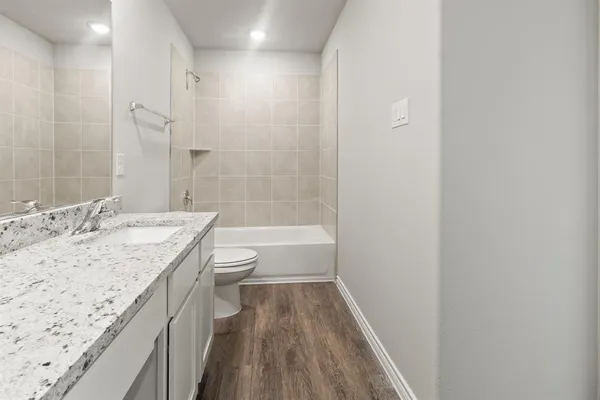 a bathroom with a granite countertop sink a toilet and shower