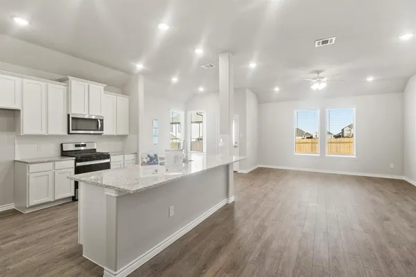 a large kitchen with kitchen island a sink dishwasher a stove and a refrigerator with wooden floor