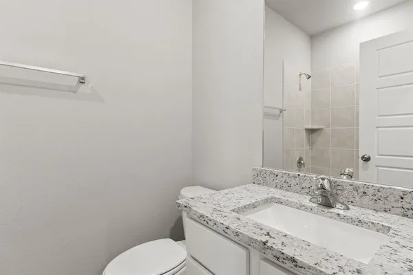 a bathroom with a granite countertop sink mirror vanity and toilet