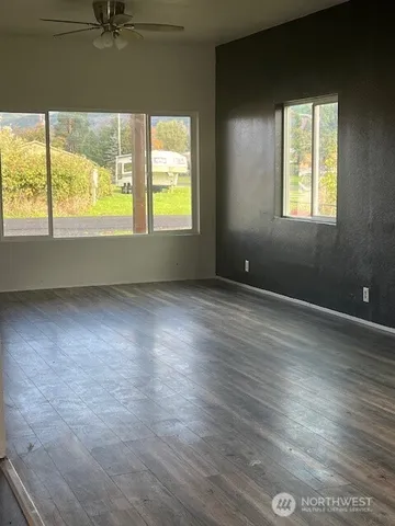 an empty room with wooden floor and windows