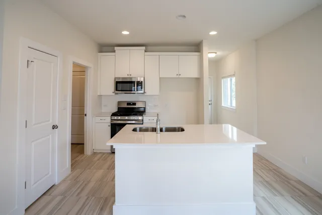 a kitchen with kitchen island a sink stainless steel appliances and white cabinets