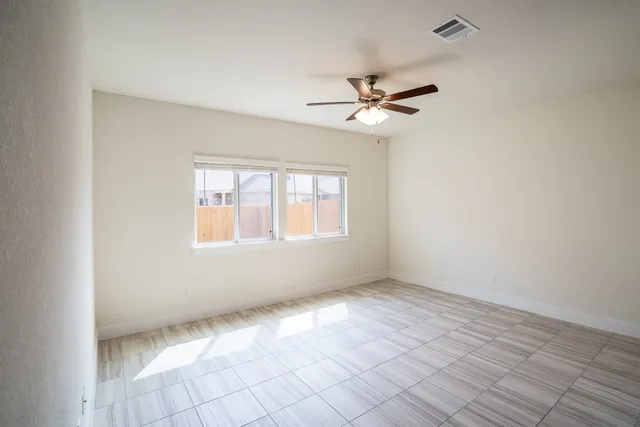 a view of a livingroom with a ceiling fan & windows
