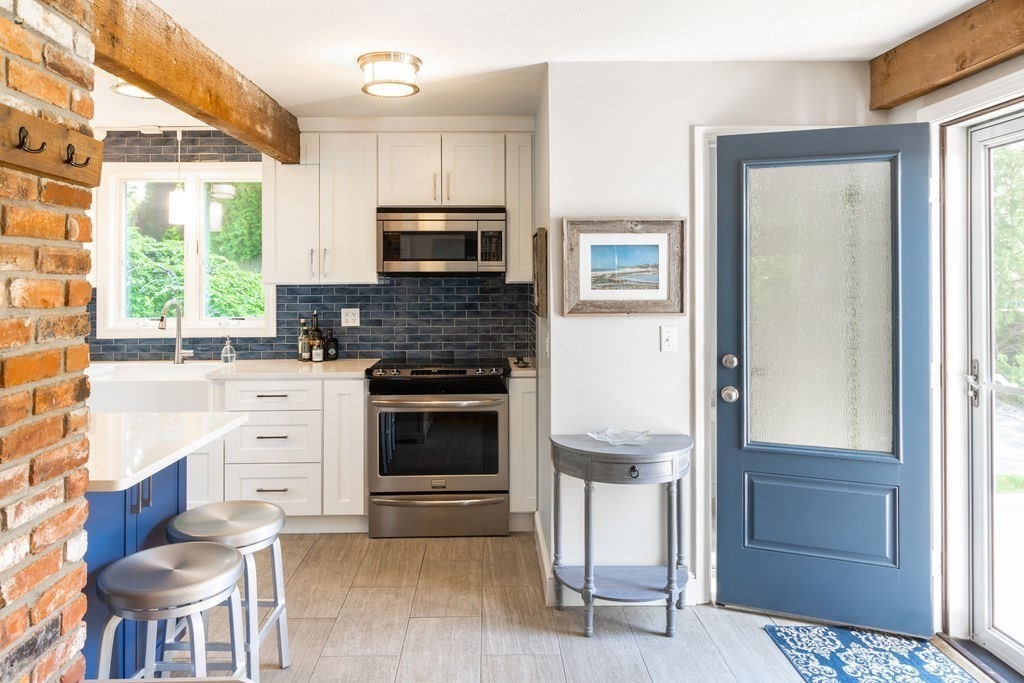85 Pitman Road Marblehead, MA 01945 - Photo 8 of 27 a kitchen with stainless steel appliances kitchen island granite countertop a stove top oven a sink and a microwave