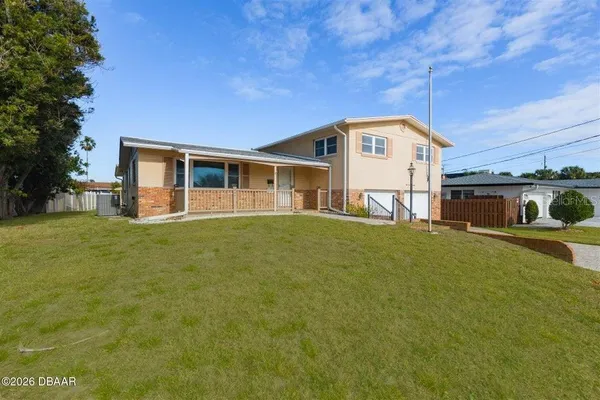 a front view of house with yard and trees in the background