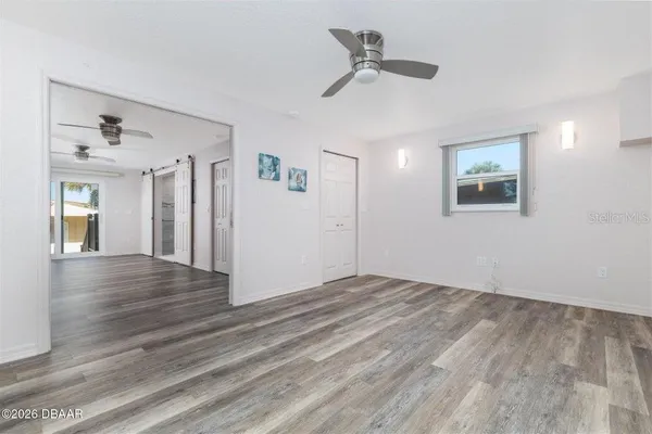 a view of an empty room with wooden floor and a window
