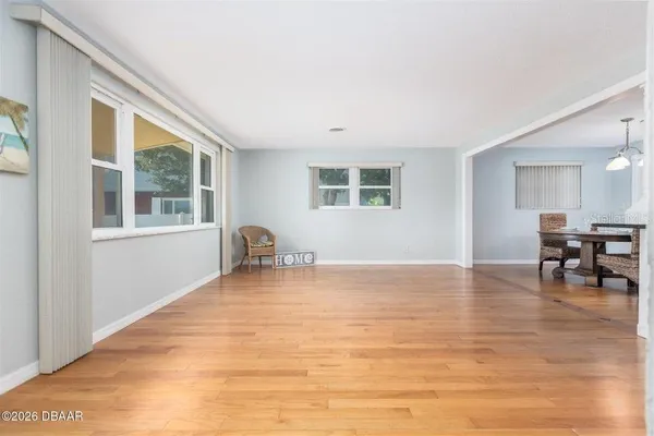 a view of an empty room with kitchen and window