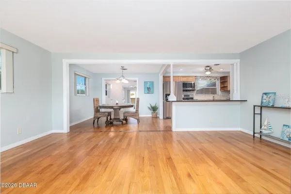 a kitchen with stainless steel appliances granite countertop a refrigerator a sink dishwasher a stove and a microwave oven on dining table with wooden floor
