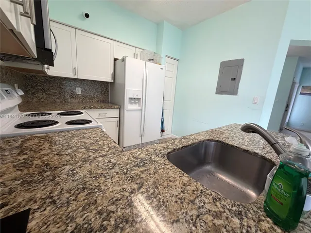 a kitchen with granite countertop a sink and a refrigerator