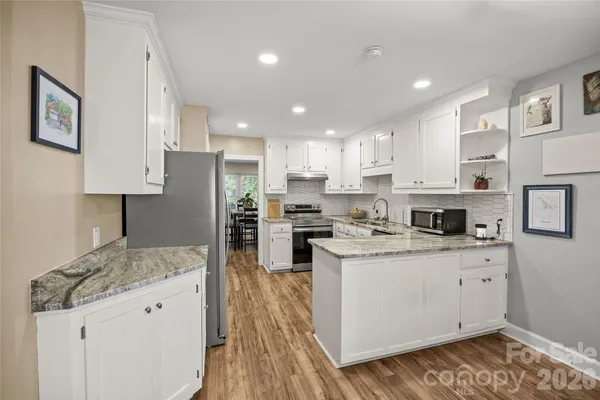 a kitchen with cabinets appliances and a wooden floor