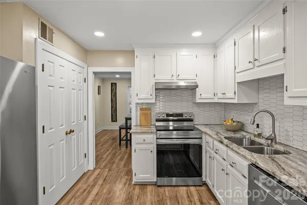 a kitchen with cabinets stainless steel appliances a sink and wooden floor