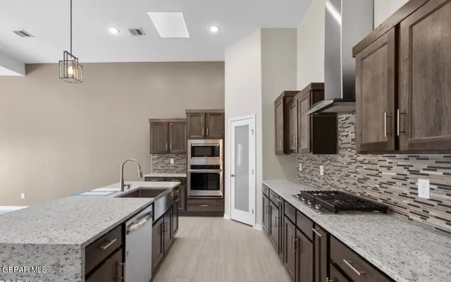 a kitchen with stainless steel appliances granite countertop a stove a sink and a refrigerator