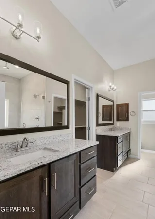 a bathroom with a granite countertop double vanity sink and mirror