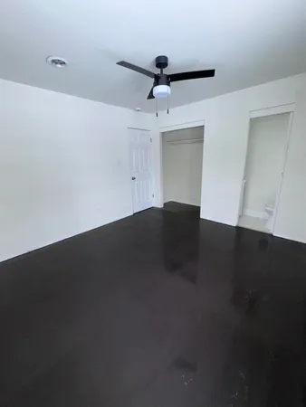 an empty room with a ceiling fan and wooden floor