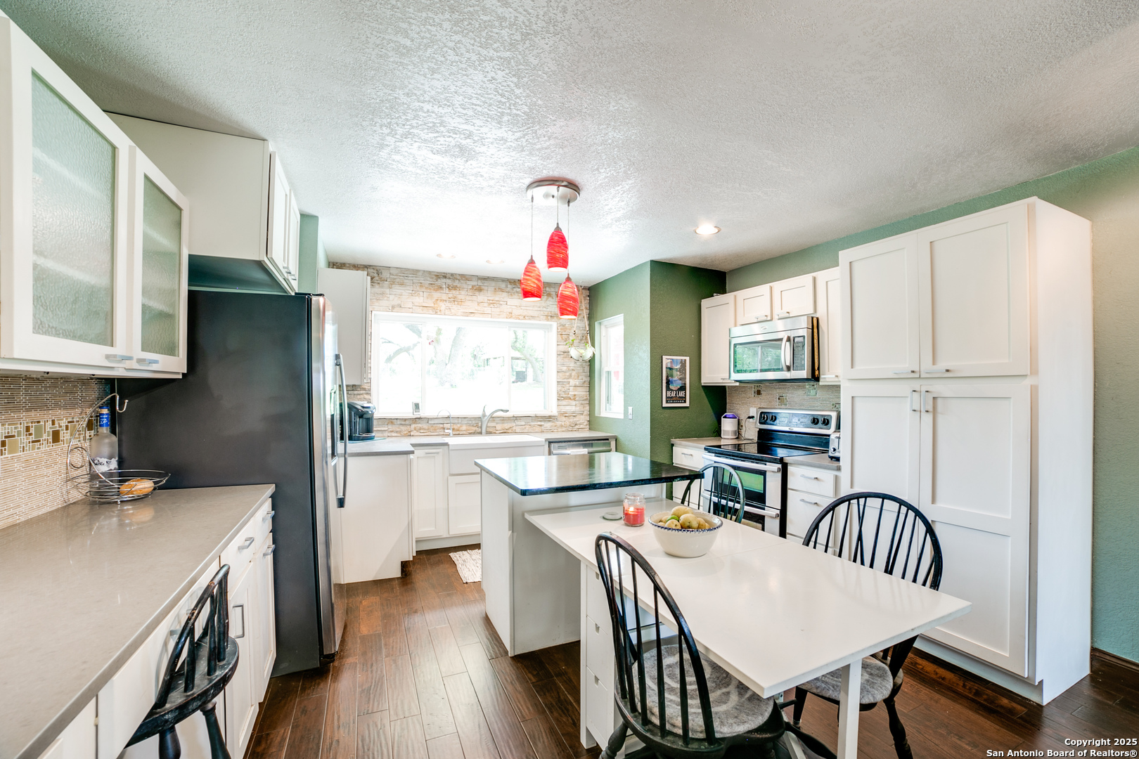 20892 Bluehill Pass Helotes, TX 78023 - Photo 26 of 36 a kitchen with stainless steel appliances granite countertop a stove top oven a sink dishwasher a dining table and chairs with wooden floor