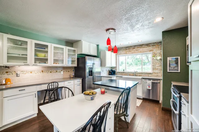 a kitchen with stainless steel appliances a dining table chairs and a refrigerator