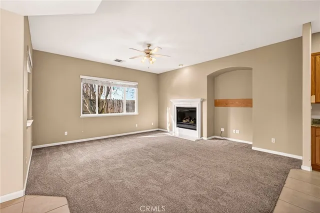 an empty room with ceiling fan and windows