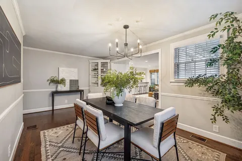 a living room with stainless steel appliances furniture a rug kitchen view and a large window