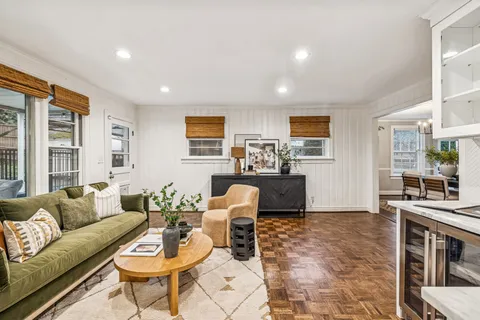 a living room with furniture a rug kitchen view and a window