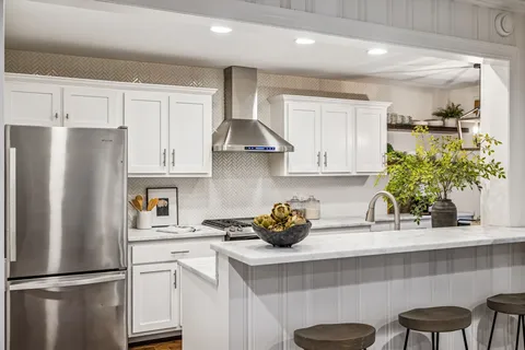a kitchen with stainless steel appliances a refrigerator a stove a sink and chairs