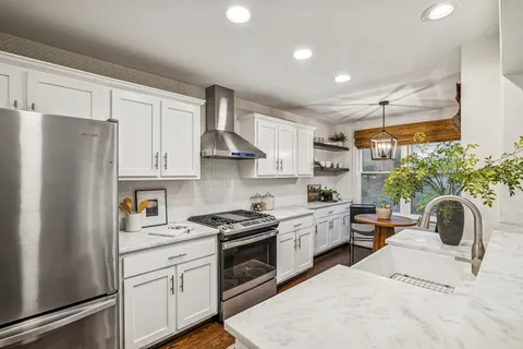 a kitchen with stainless steel appliances granite countertop a stove a sink and a white cabinets
