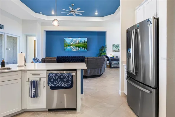 a large white kitchen with stainless steel appliances granite countertop a stove a sink a refrigerator and white cabinets with wooden floor