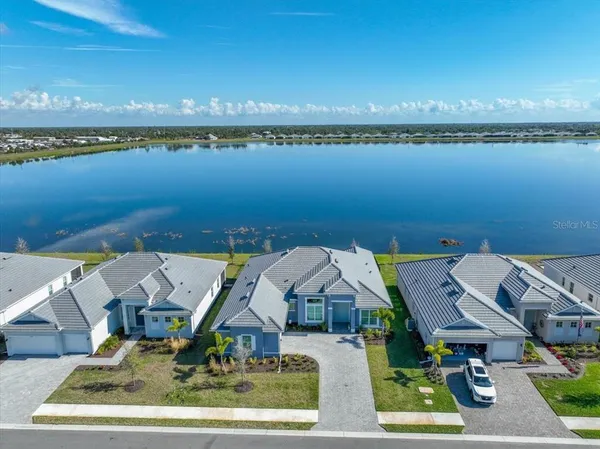 an aerial view of ocean and residential houses with outdoor space