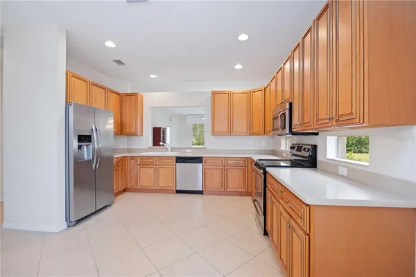 a kitchen with stainless steel appliances granite countertop a stove top oven a sink dishwasher and a refrigerator with wooden cabinets