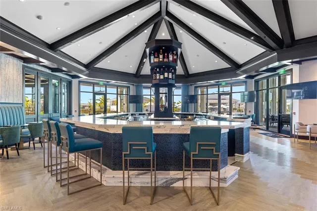 a dining hall with stainless steel appliances granite countertop a table chairs and a chandelier