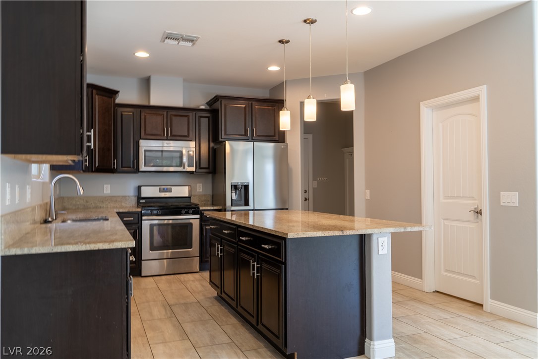 11045 Elk Sands Road Las Vegas, NV 89179 - Photo 14 of 67 Rich dark cabinetry and expansive granite countertops highlight this modern cooking space.