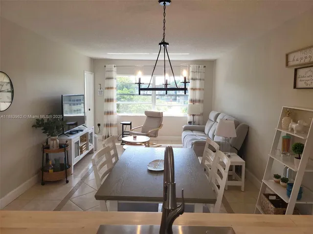 a living room with furniture a chandelier and kitchen view