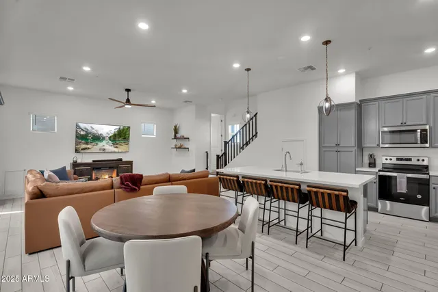 a living room with stainless steel appliances kitchen island granite countertop a table chairs refrigerator and microwave