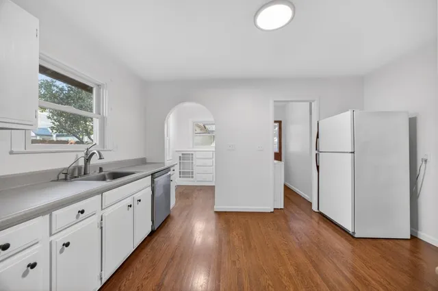 a kitchen with a refrigerator a sink and wooden floors