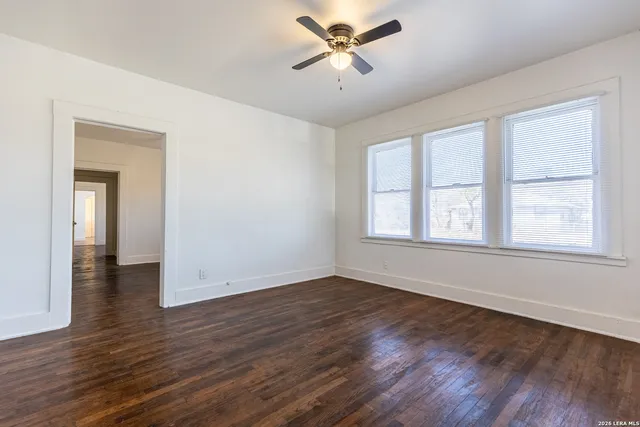 a view of empty room with wooden floor and fan