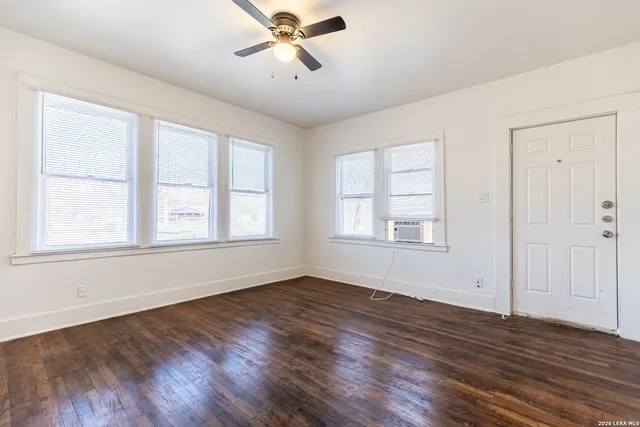 a view of empty room with wooden floor and fan