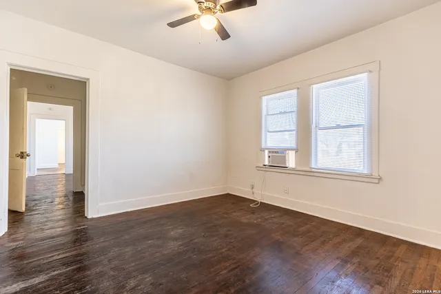 a view of an empty room with wooden floor and a window