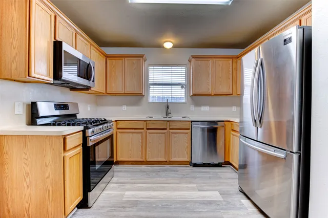a kitchen with stainless steel appliances granite countertop a sink cabinets and wooden floor